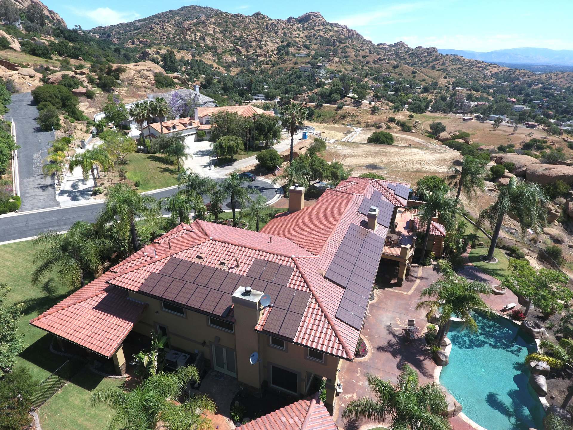 Aerial view of a Southwest-style home with a red tile roof and rooftop solar panels
