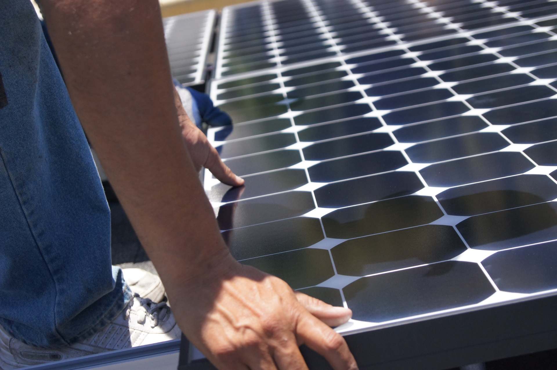 Solar installer setting a panel into place on a rooftop
